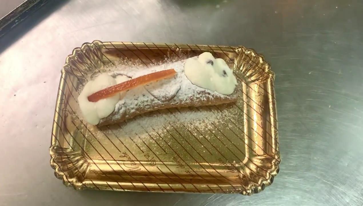 Cannolo appena riempito su un vassoio dorato
