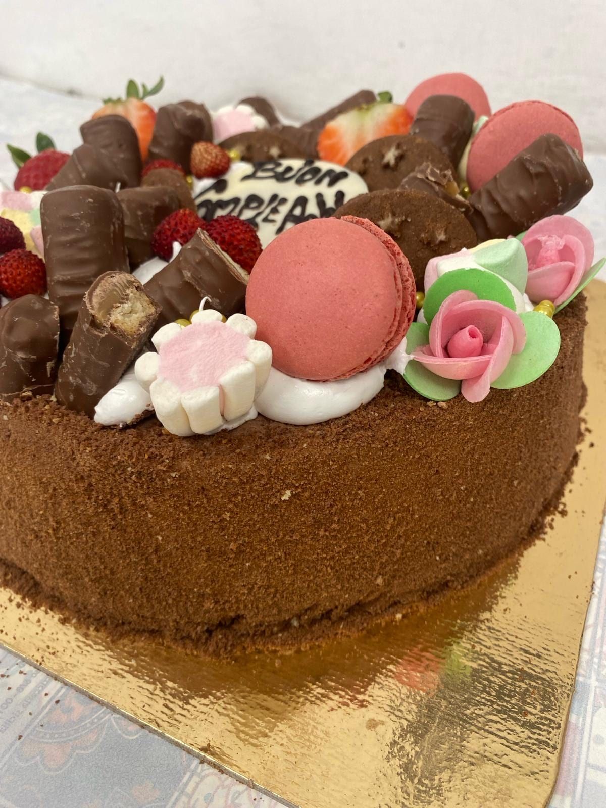 Torta di compleanno al cioccolato decorata con macaron e fiori di zucchero